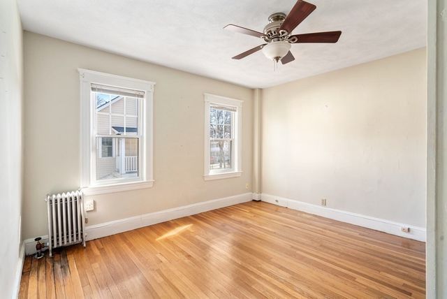 a view of an empty room with window and wooden floor