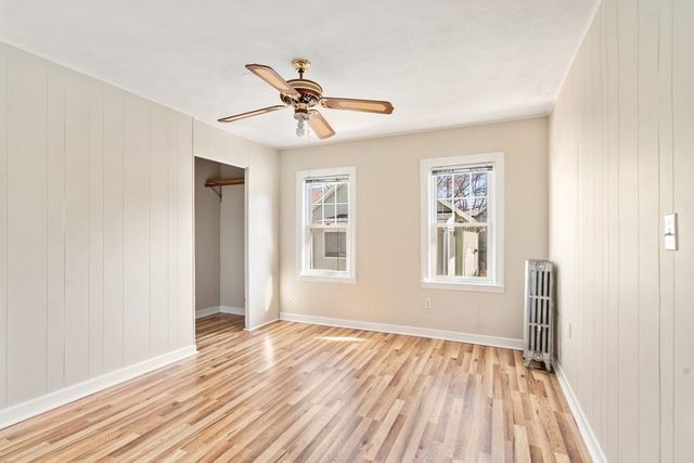 a view of empty room with wooden floor and fan
