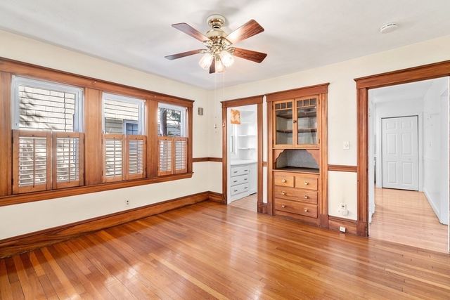 a view of an empty room with window and wooden floor