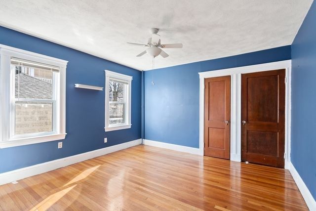 a view of an empty room with window and wooden floor