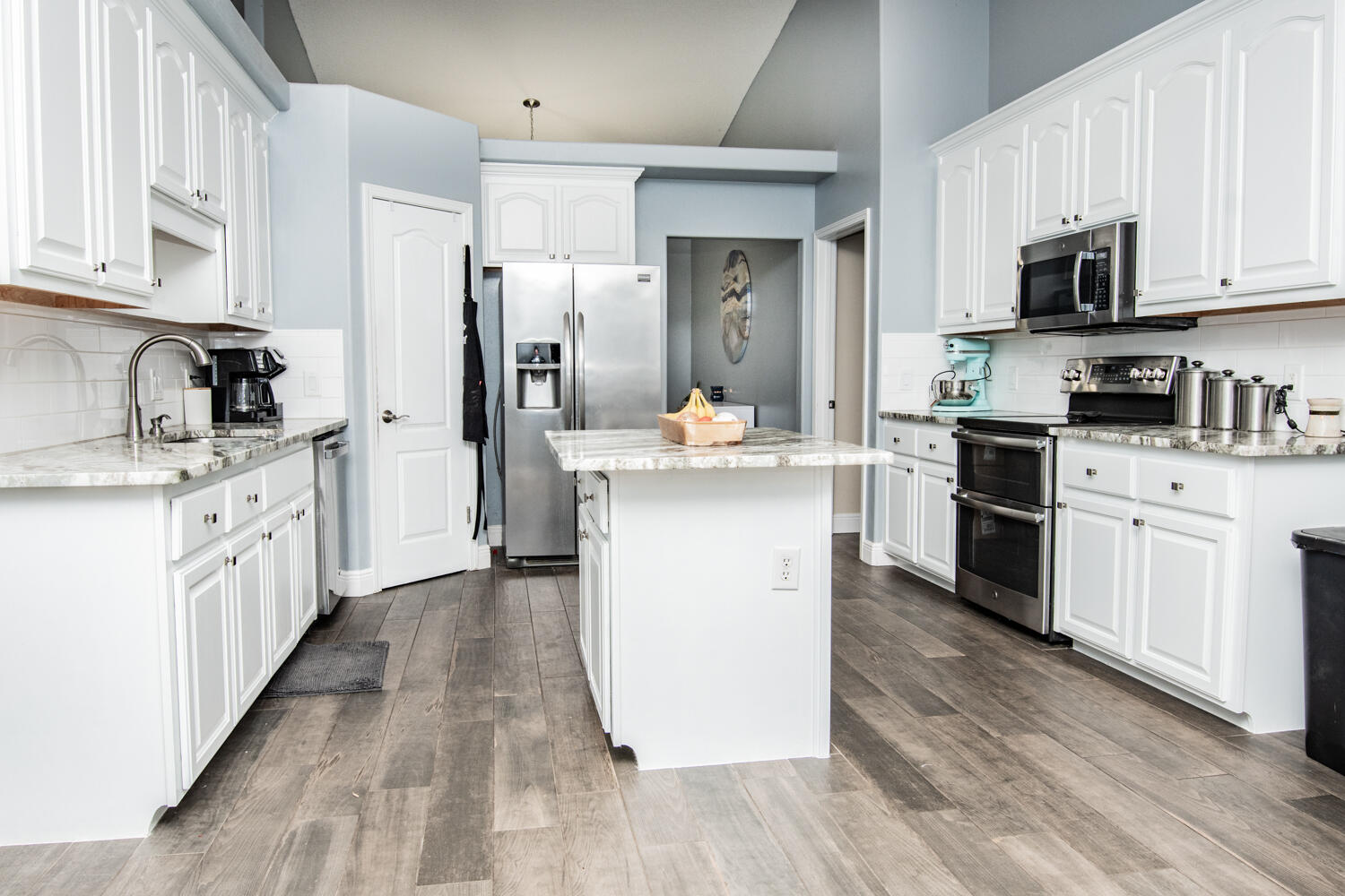 530 Vulpes Sanctuary Loop Crestview, FL 32536 - Photo 11 of 31 a kitchen with stainless steel appliances kitchen island granite countertop a refrigerator a sink dishwasher a stove top oven a refrigerator with white cabinets and wooden floor