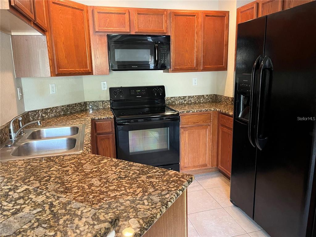 4600 East Moody Boulevard, Unit 1A Bunnell, FL 32110 - Photo 3 of 7 a kitchen with stainless steel appliances granite countertop a refrigerator stove and microwave