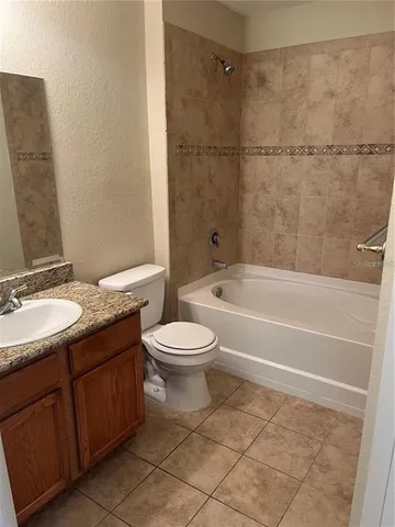 a bathroom with a granite countertop bathtub shower sink vanity and toilet