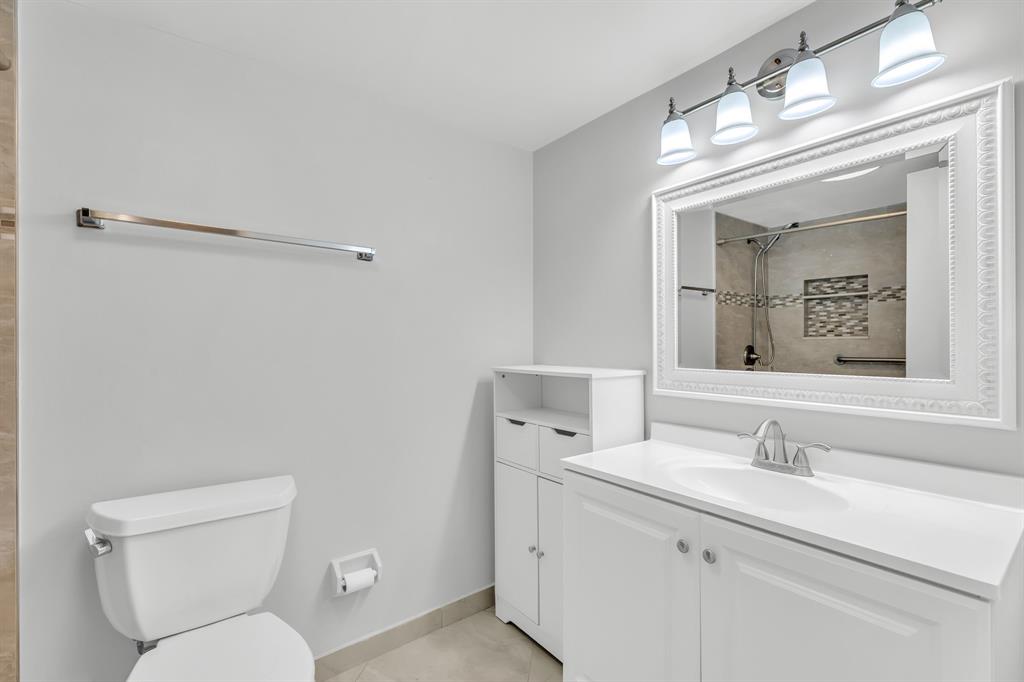 13950 Vía Flora, Unit B Delray Beach, FL 33484 - Photo 14 of 28 a bathroom with a toilet sink and mirror