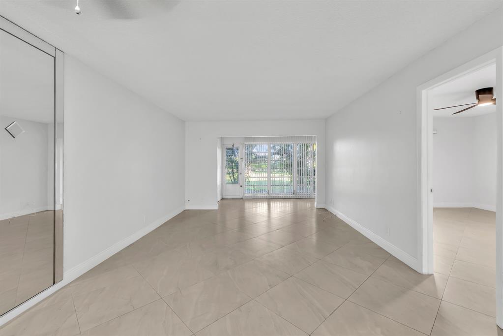 13950 Vía Flora, Unit B Delray Beach, FL 33484 - Photo 9 of 28 a view of an empty room with wooden floor and a window