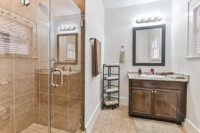 a bathroom with a granite countertop sink a mirror and a shower