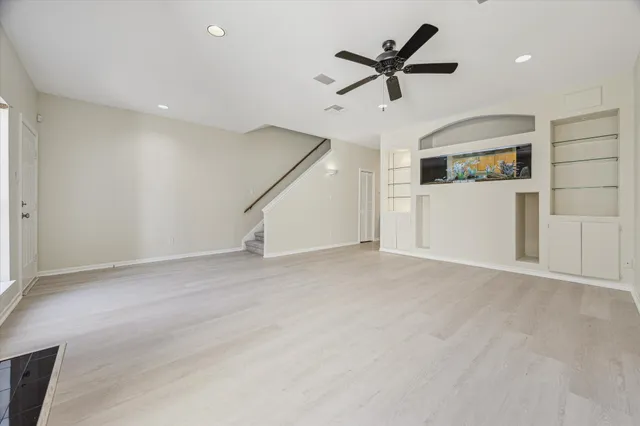 an empty room with ceiling fan and window