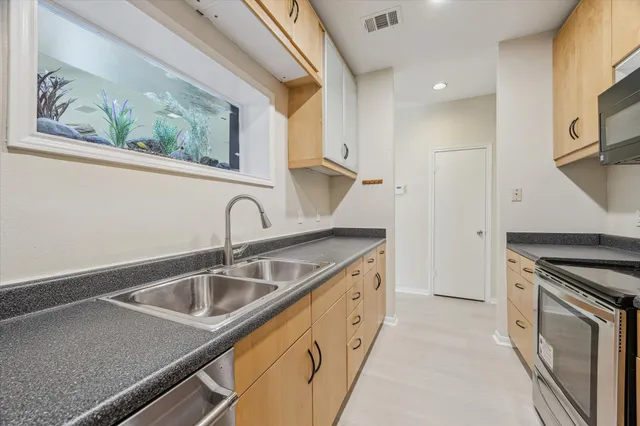 a kitchen with stainless steel appliances granite countertop a sink a stove and a refrigerator