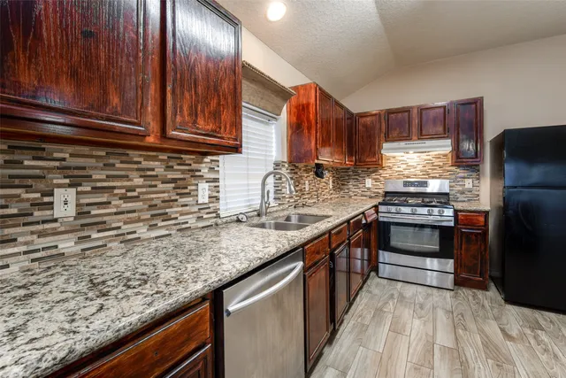 a kitchen with granite countertop wooden cabinets stainless steel appliances and a counter space