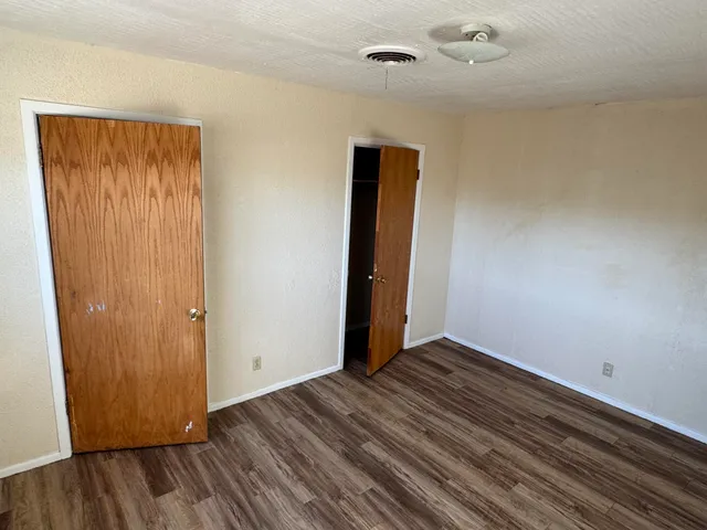 an empty room with wooden floor and closet area