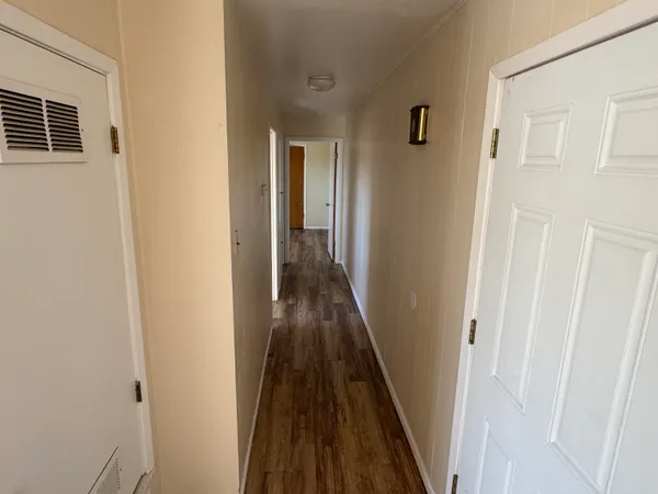 a view of a hallway with wooden floor and staircase