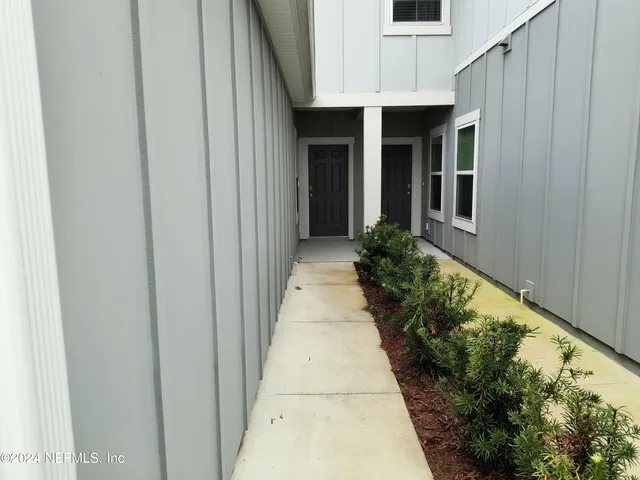 a view of a pathway of a house with potted plants