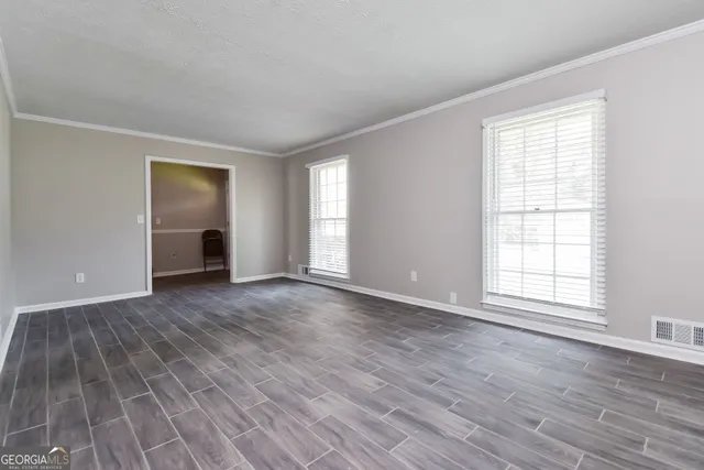 an empty room with wooden floor and windows