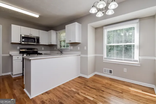 a kitchen with stainless steel appliances granite countertop a sink dishwasher a stove a microwave oven with cabinets and wooden floor