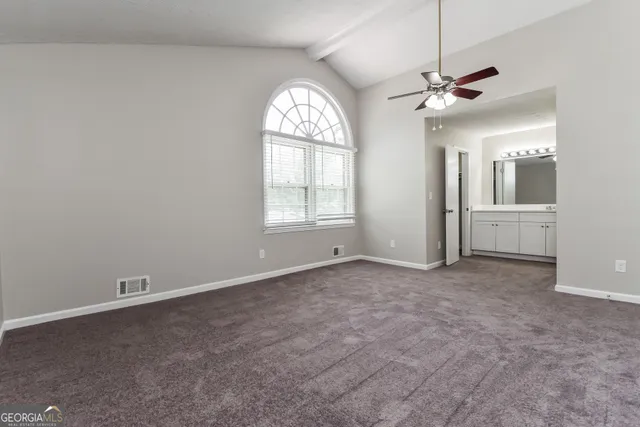 an empty room with chandelier fan and windows