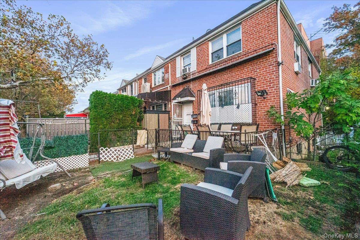 a view of a patio with couches table and chairs with wooden fence and plants