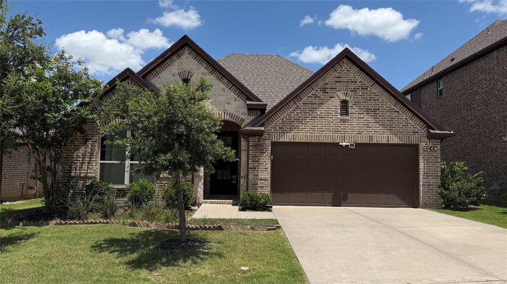 14712 Spitfire Trail Fort Worth, TX 76262 - Photo 2 of 25 Brick and stone facade featuring a two-car garage, pitched roofline, arched entry, and mature landscaping