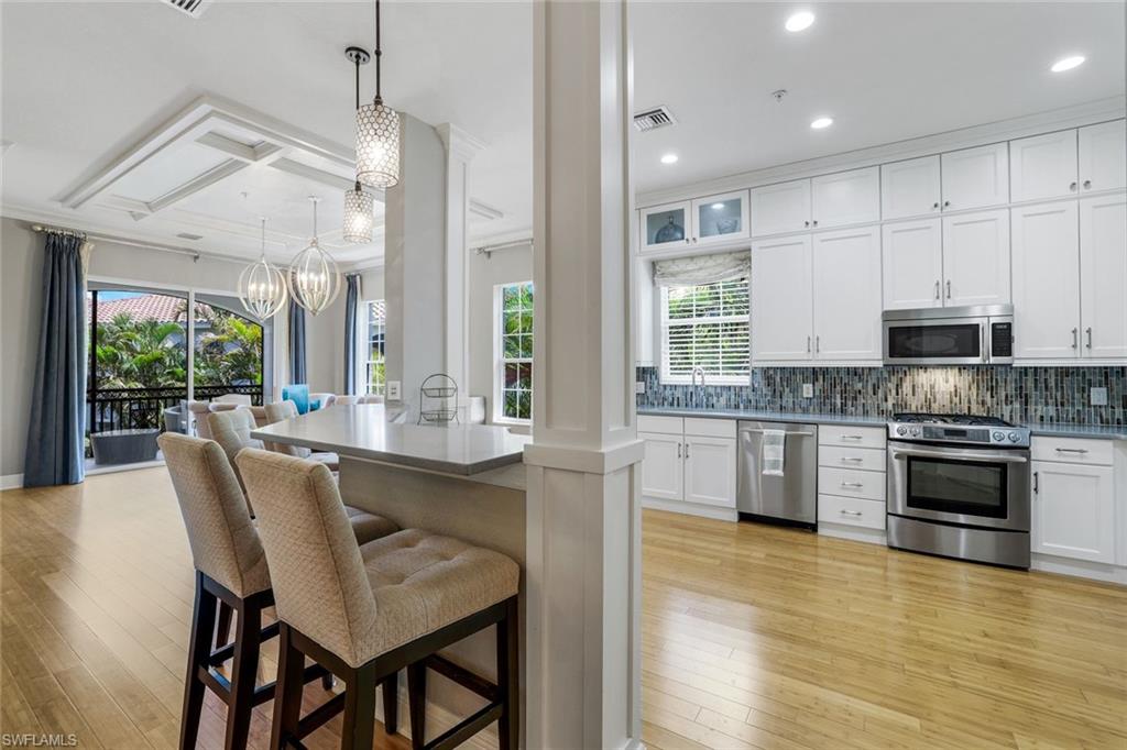 9053 Cascada Way, Unit 202 Naples, FL 34114 - Photo 11 of 45 a kitchen with stainless steel appliances granite countertop a kitchen island hardwood floor sink and stove