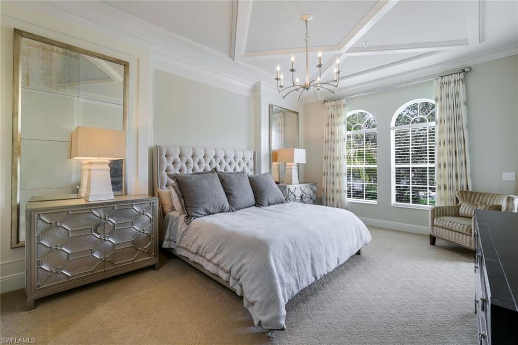 9053 Cascada Way, Unit 202 Naples, FL 34114 - Photo 13 of 45 a spacious bedroom with a bed chandelier and window