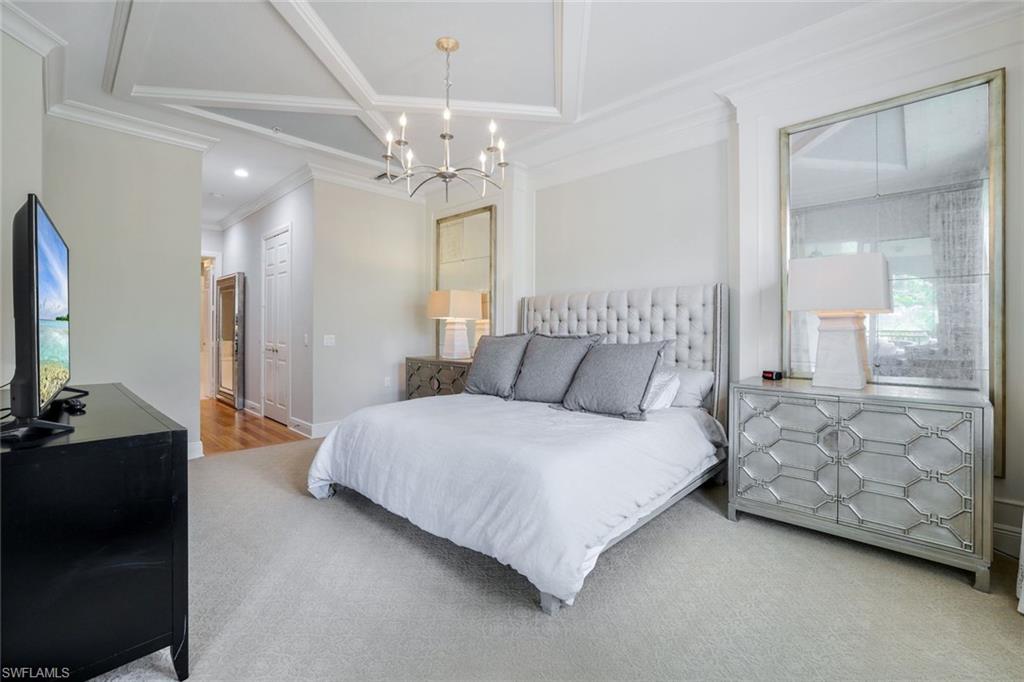 9053 Cascada Way, Unit 202 Naples, FL 34114 - Photo 14 of 45 a spacious bedroom with a bed and a chandelier