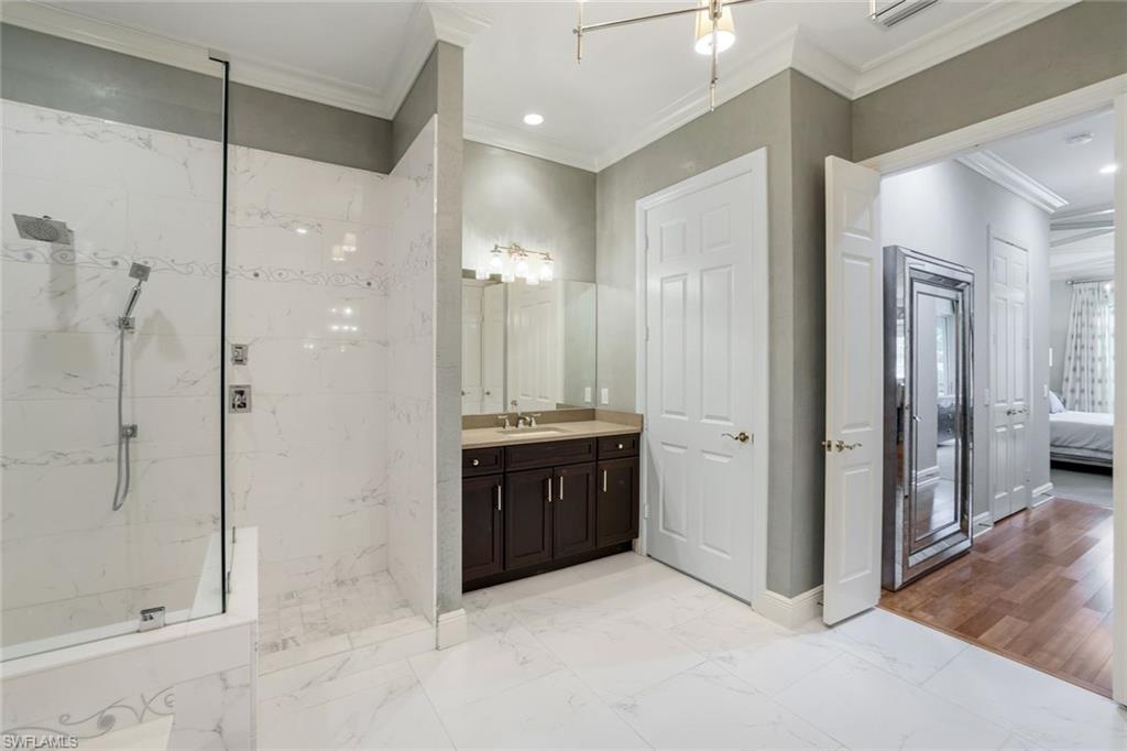 9053 Cascada Way, Unit 202 Naples, FL 34114 - Photo 15 of 45 a large bathroom with a glass shower door a sink and a mirror