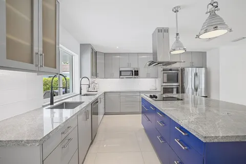 a large kitchen with stainless steel appliances granite countertop a sink a stove and a refrigerator