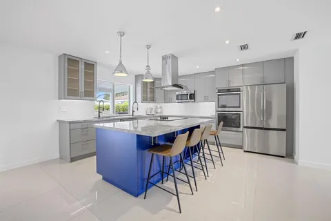 a kitchen with kitchen island granite countertop a sink a center island stainless steel appliances and cabinets