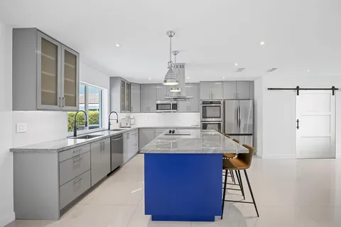 a kitchen with stainless steel appliances kitchen island granite countertop a sink stove and refrigerator
