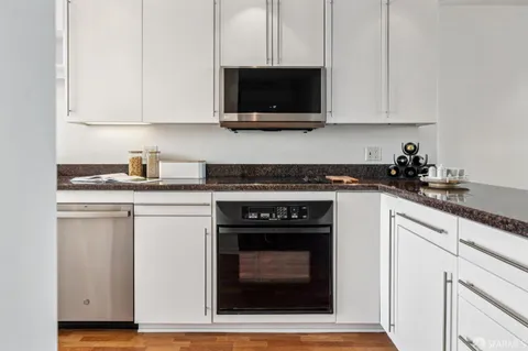 a kitchen with stainless steel appliances granite countertop a stove top oven microwave and cabinets