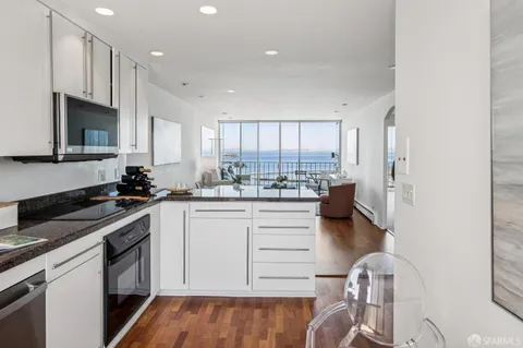 a kitchen with granite countertop white cabinets and white appliances