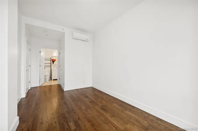 a view of a hallway with wooden floor and a bathroom
