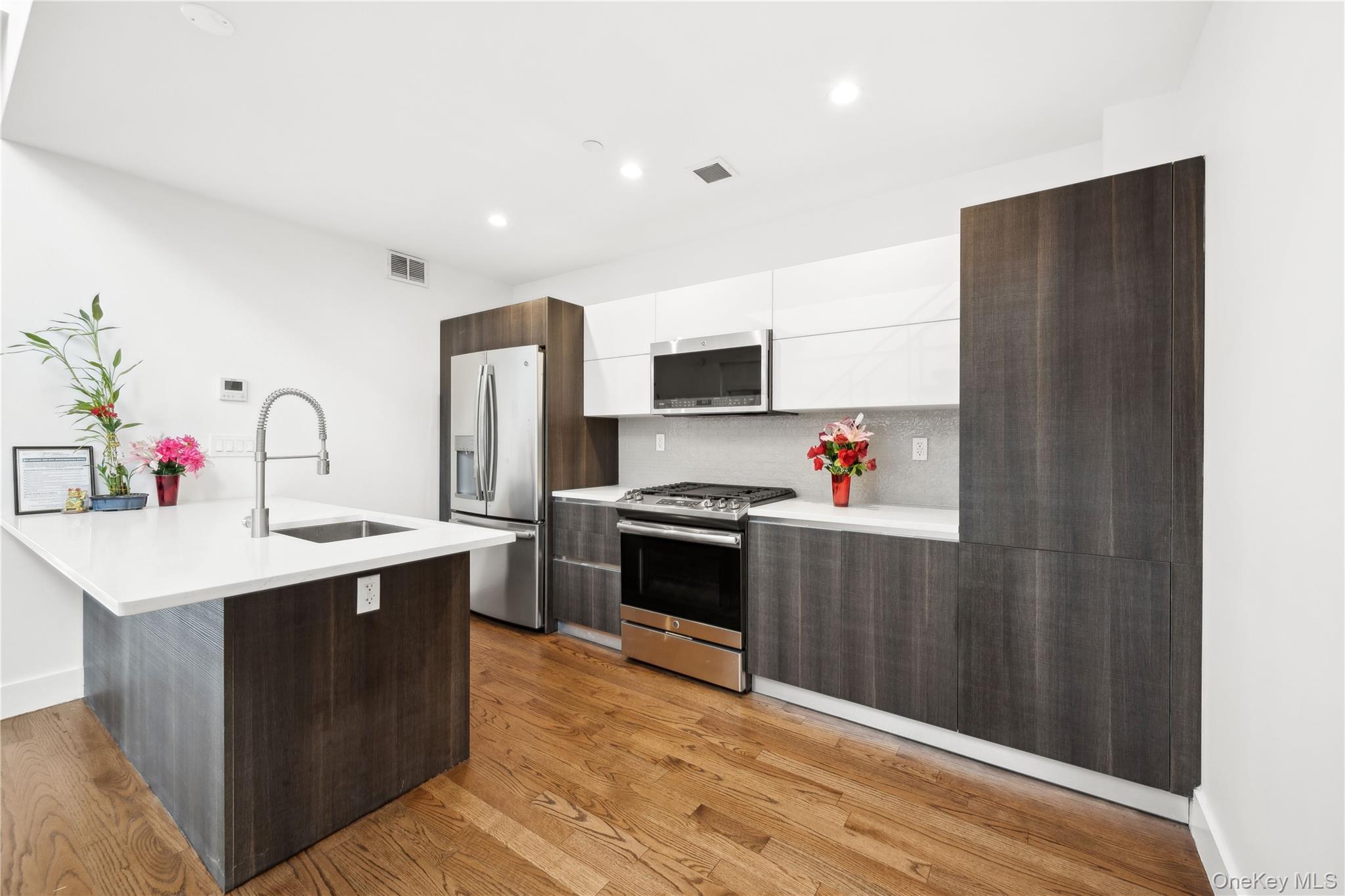 109-19 72nd Road, Unit PH7F Queens, NY 11375 - Photo 7 of 27 a kitchen with stainless steel appliances a sink dishwasher a refrigerator and a stove with wooden floor