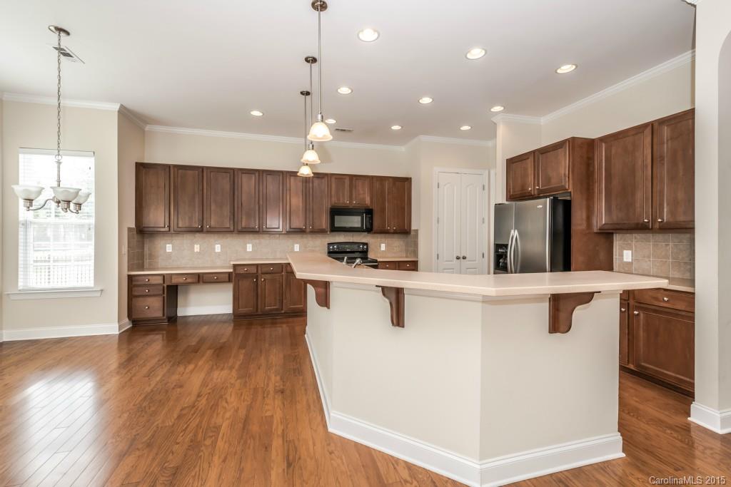 312 Miners Cove Way Fort Mill, SC 29708 - Photo 6 of 24 a kitchen with kitchen island granite countertop wooden floors white cabinets and stainless steel appliances