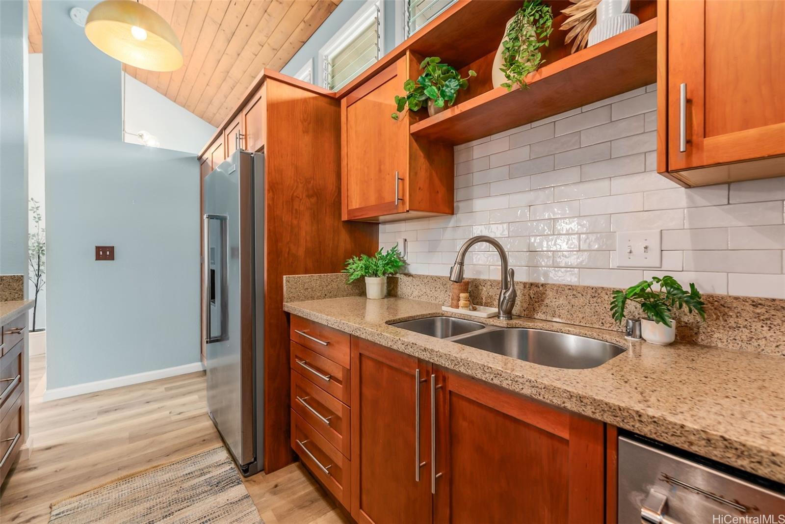 45-995 Wailele Road, Unit 55 Kaneohe, HI 96744 - Photo 6 of 24 a kitchen with granite countertop a sink and wooden cabinets