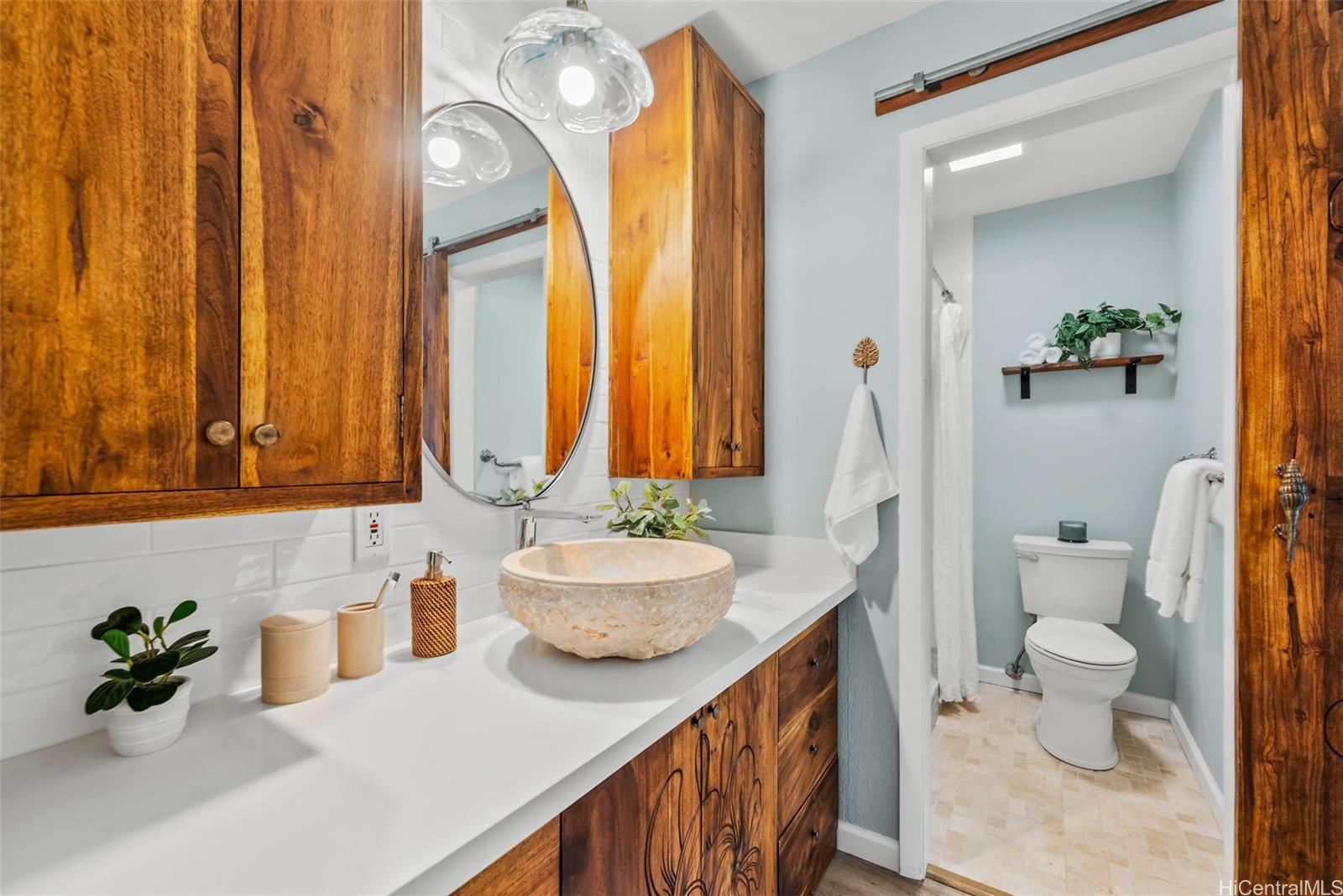 45-995 Wailele Road, Unit 55 Kaneohe, HI 96744 - Photo 7 of 24 a bathroom with a granite countertop sink mirror and a toilet