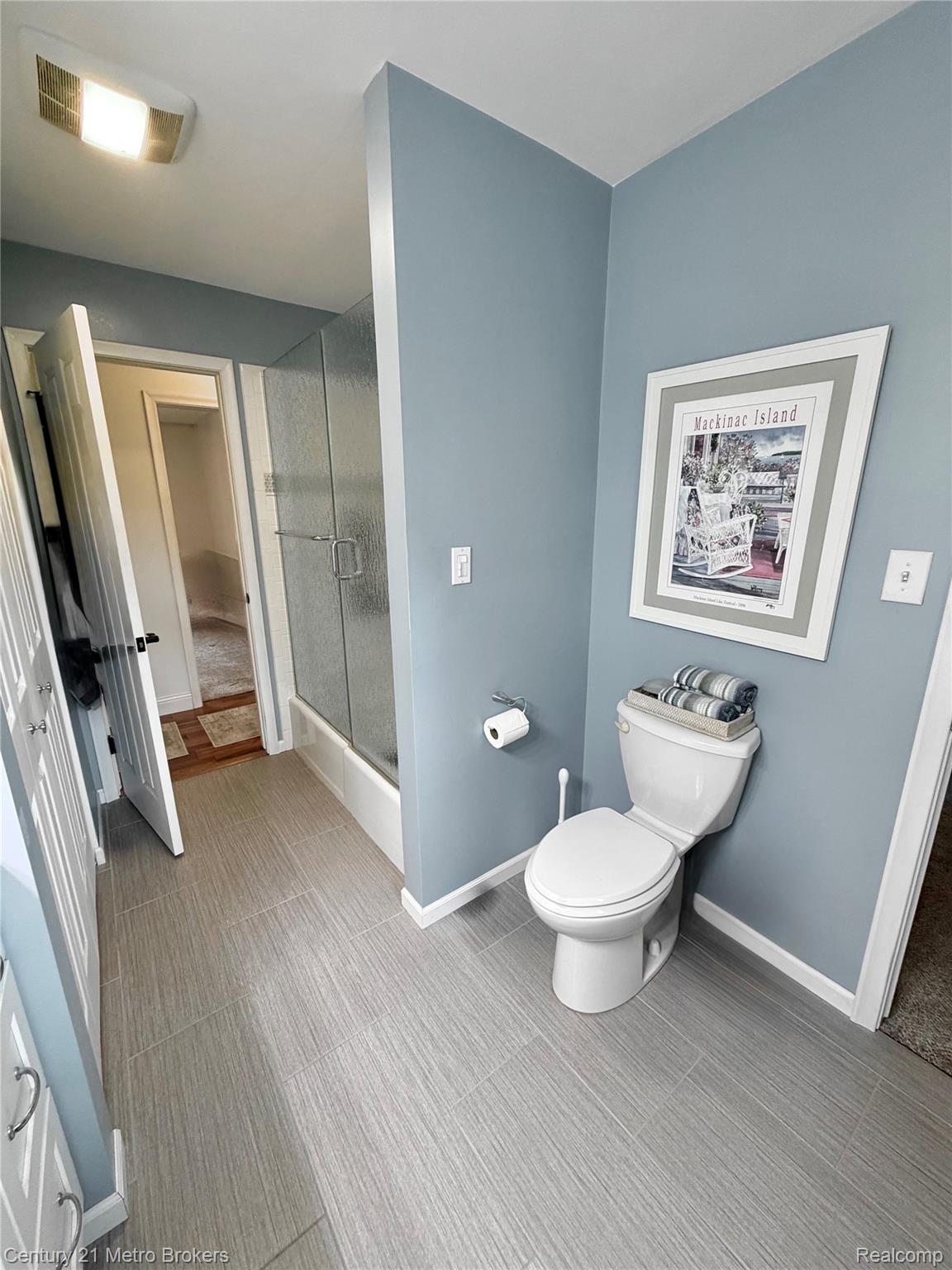 3259 North Seymour Road Flushing, MI 48433 - Photo 32 of 49 Bathroom featuring wood-finish tile flooring, a glass-enclosed shower, a white toilet, and light blue walls