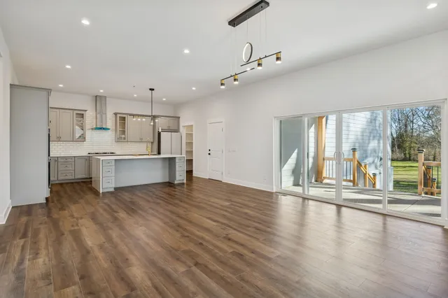 a view of an empty room with wooden floor and a fireplace