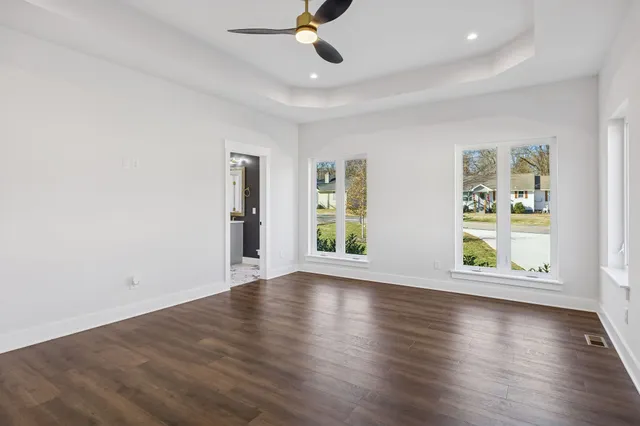 an empty room with wooden floor and windows