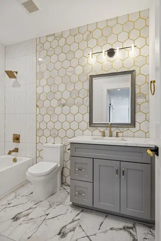 a bathroom with a granite countertop toilet a sink and a bathtub