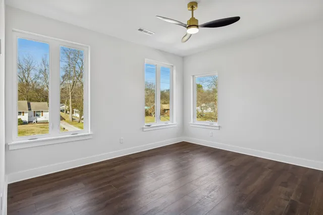 an empty room with wooden floor and windows