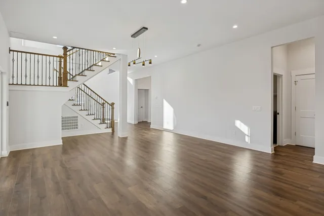 a view of an empty room with wooden floor fireplace and a window