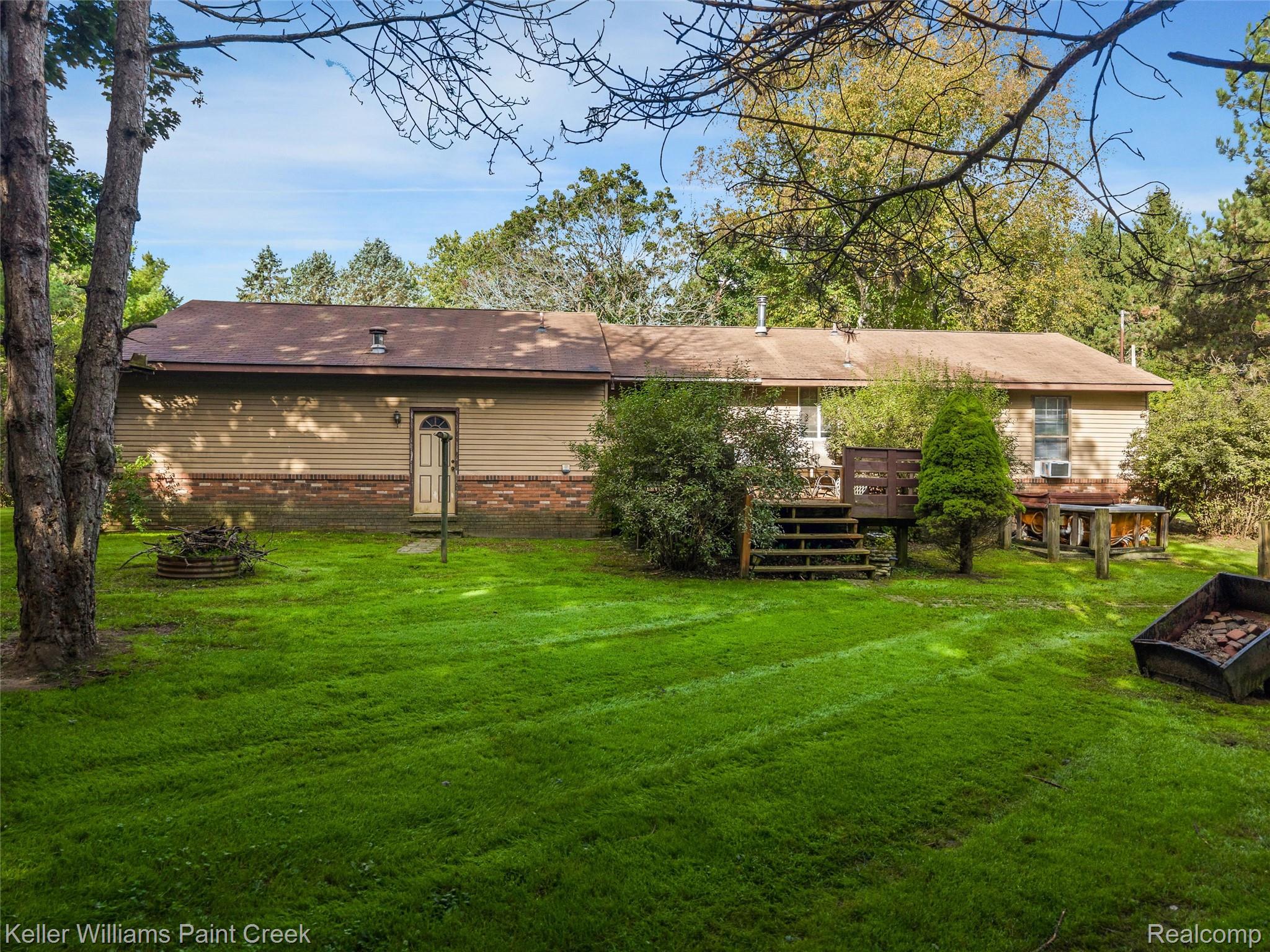 5077 Pinckney Road Howell, MI 48843 - Photo 32 of 39 Expansive backyard featuring a manicured lawn, wood siding, and a multi-level wooden deck