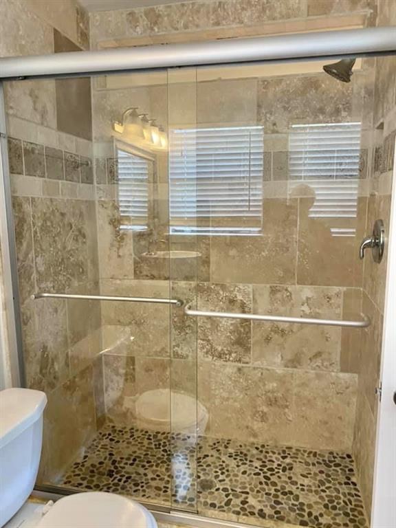 4404 Travis Country Circle, Unit G4 Austin, TX 78735 - Photo 4 of 15 A pebble-floored shower with sliding glass doors defines this elegant bathroom space.