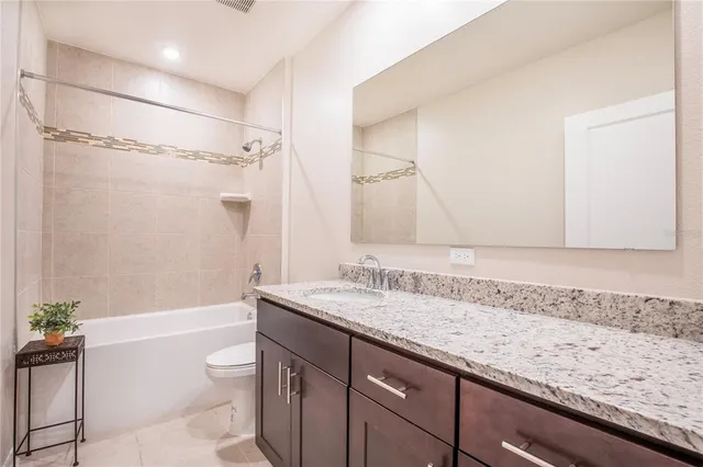 a bathroom with a granite countertop sink a toilet and shower