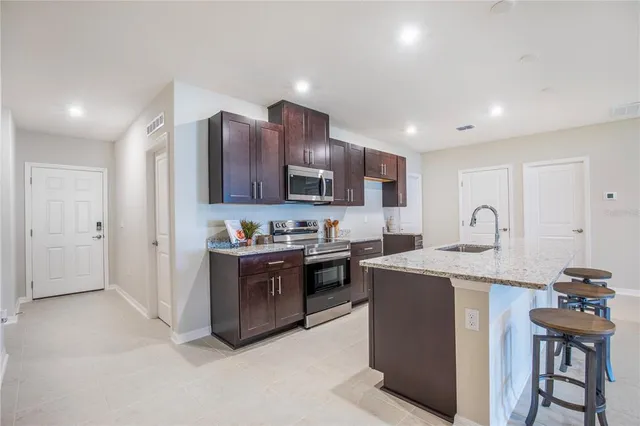 a large kitchen with stainless steel appliances granite countertop a stove refrigerator and a sink