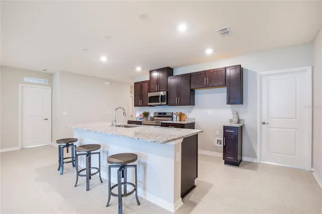 a kitchen with stainless steel appliances granite countertop a sink a stove a refrigerator and island with wooden floor