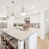 a kitchen with kitchen island a stove a refrigerator a sink a stove and white cabinets with wooden floor