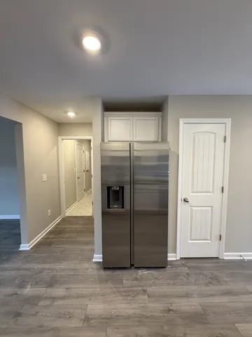 a view of a refrigerator in kitchen and an empty room