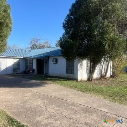 a view of a house with a yard and large tree
