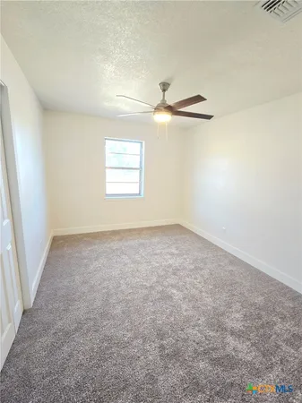 a view of an empty room with a window and a kitchen